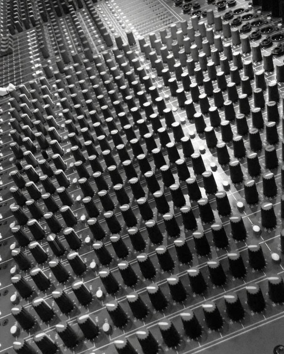 A field of knobs across an analog mixing board, in black and white