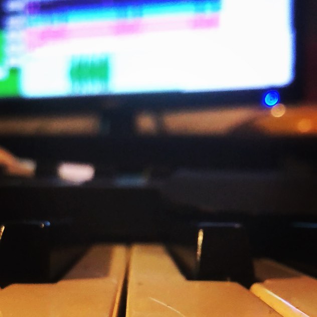 MIDI keys up close with a DAW session glowing on the studio display behind